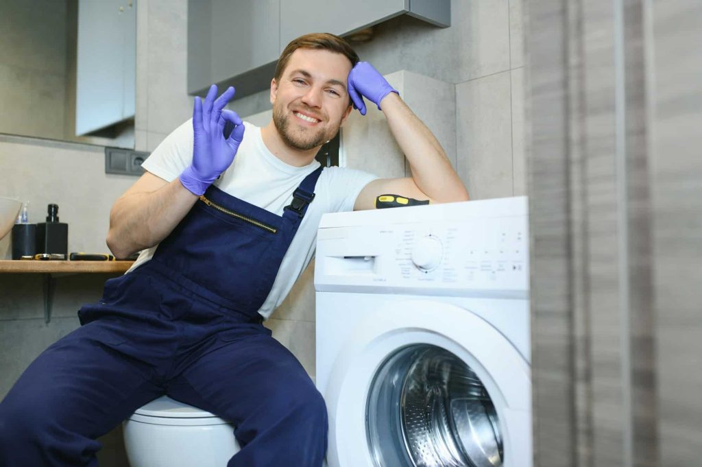 working man plumber repairs a washing machine